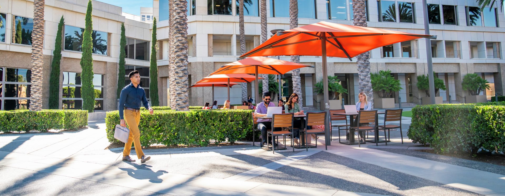 Exterior view of people at The Commons outdoor workspace at the 100 Spectrum Center Drive office building in Irvine, CA.