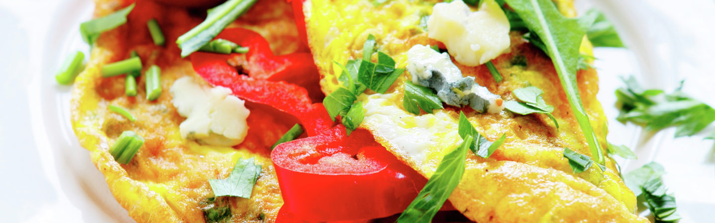 Omelette with red peppers, arugula on a white plate
