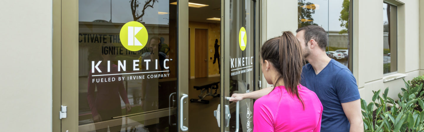 A man and woman walking into the KINETIC fitness center located ar Irvine Business Center in Irvine, CA