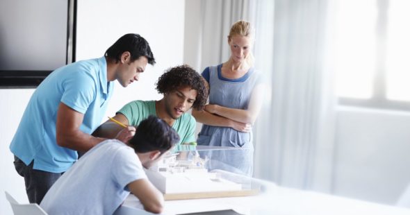 A group of young architects looking over a model together