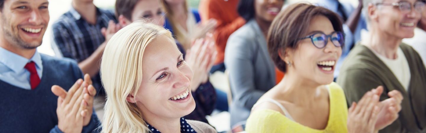 A diverse group of people laughing and applauding during a conference
