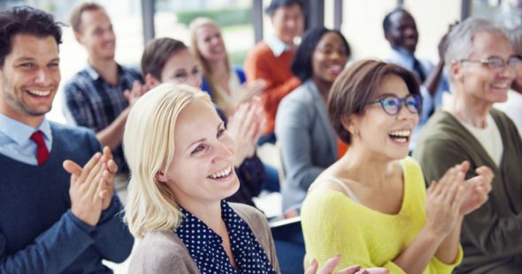A diverse group of people laughing and applauding during a conference