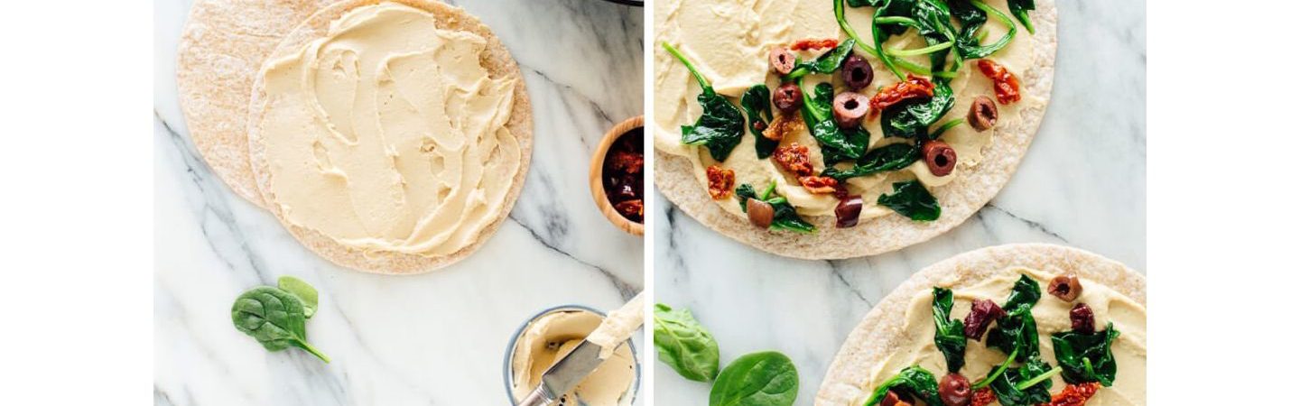 Photo of flatbread that has been spread with hummus and topped with spinach and olives