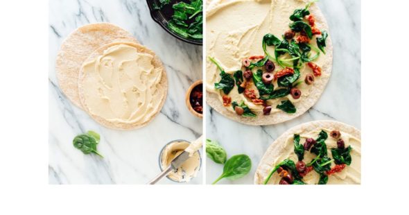 Photo of flatbread that has been spread with hummus and topped with spinach and olives