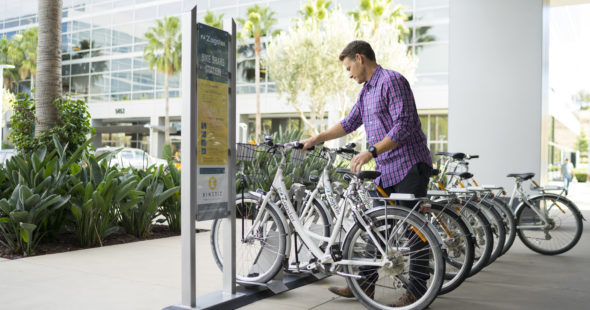 Photography of a man renting a Zagster bike from the bike share program offered by Irvine Company