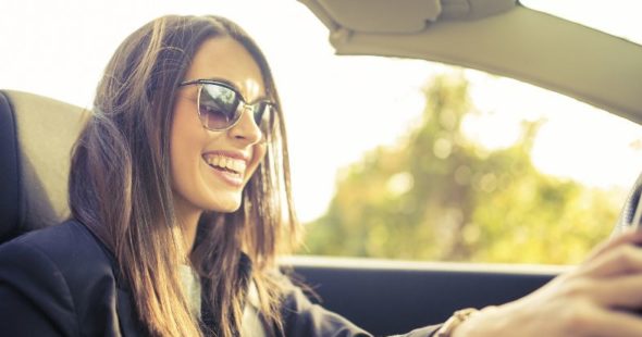 Woman wearing sunglasses and smiling while driving a convertible