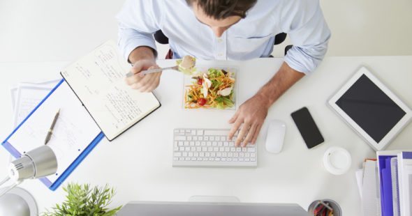Woman eating lunch and working at her desk at the same time