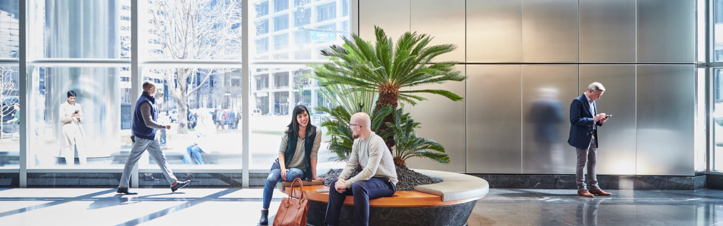 Photography of people walkthough through and sitting at the bench in the atrium at 71 South Wacker in Chicago, IL