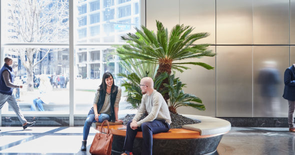 Photography of people walkthough through and sitting at the bench in the atrium at 71 South Wacker in Chicago, IL