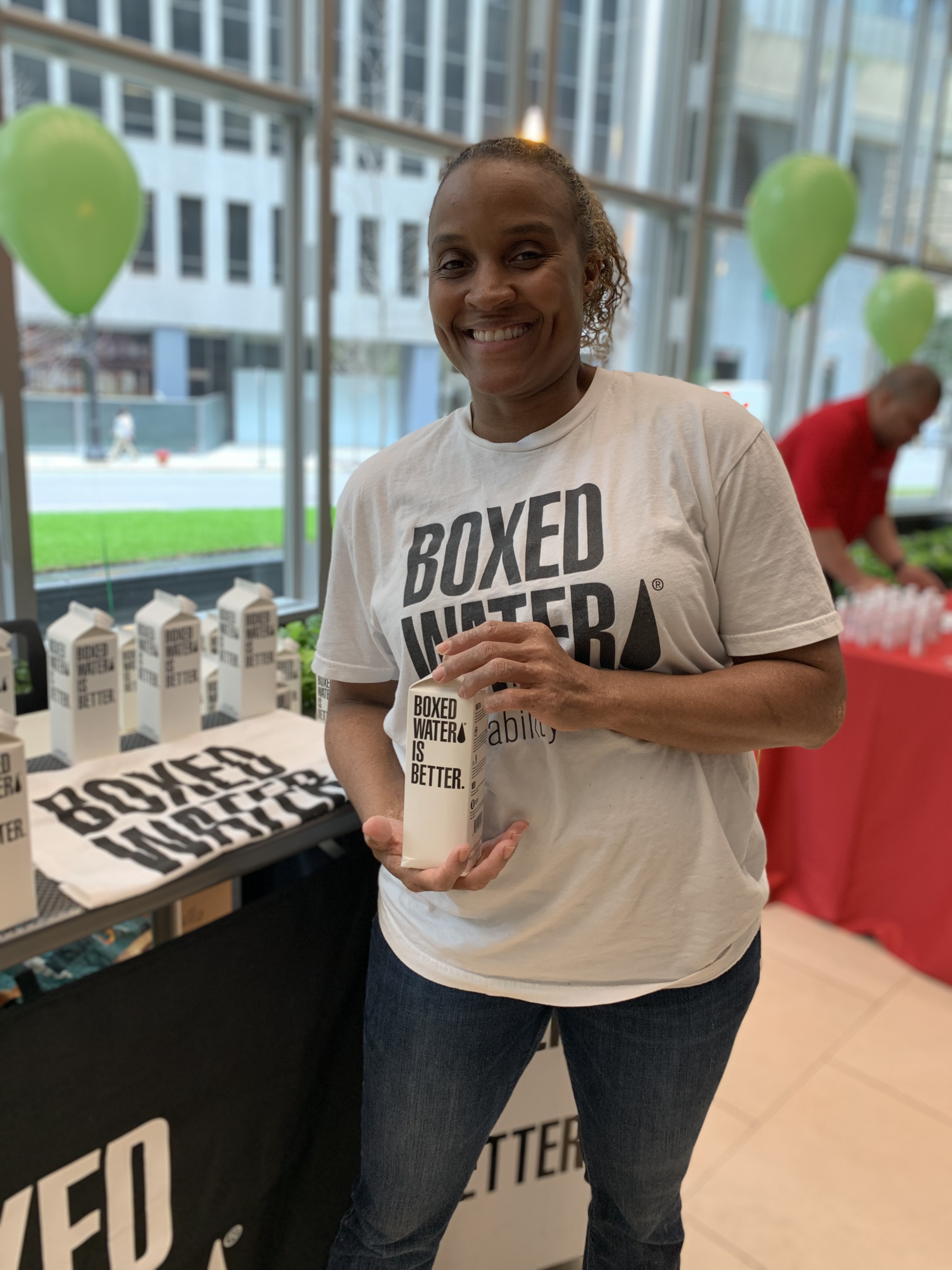 Photography of a woman holding a Boxed Water branded carton of water for the Chicago Elevate collection