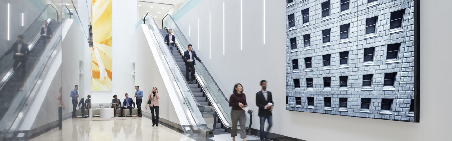 Photo of the digital media wall and people going down the escalator at The Exchange in 71 South Wacker, Chicago, IL