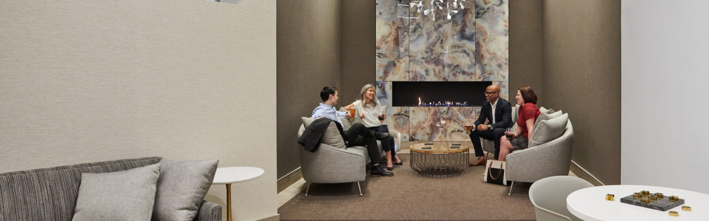 Photography of business people having a conversation near a fireplace with soft seating at The Exchange in 71 South Wacker in Chicago, IL