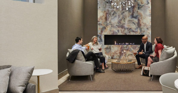 Photography of business people having a conversation near a fireplace with soft seating at The Exchange in 71 South Wacker in Chicago, IL
