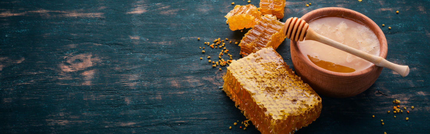 Honey in a bowl and honeycomb on a dark wooden table