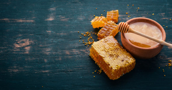 Honey in a bowl and honeycomb on a dark wooden table
