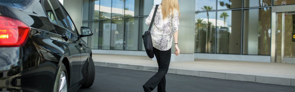 Photo of a woman walking away from a car towards the entrance of One La Jolla Center in San Diego, CA